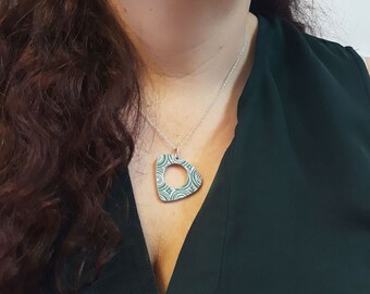 May include: A silver chain necklace with a green and white patterned pendant shaped like a triangle with a circle cut out of the center.
