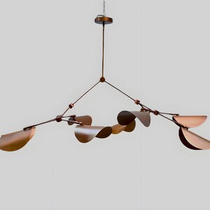 以下が含まれることがあります： ユニークなデザインのモダンな銅色のシャンデリア。 複数の湾曲した葉の形をしたシェードと、外側に伸びる複数のアームを備えた中央のステムが特徴です。 光は単一のポイントから吊り下げられています。