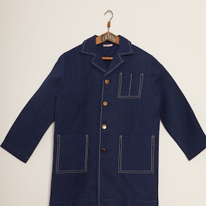 May include: A navy blue long-sleeved jacket with a collared neckline and gold buttons. The jacket has two large pockets on the front and a smaller pocket on the chest. The jacket is lined with white stitching.