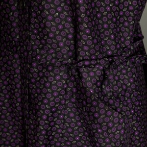 May include: A black dress with a purple floral pattern. The dress has a gathered waist and a ruffled hem.
