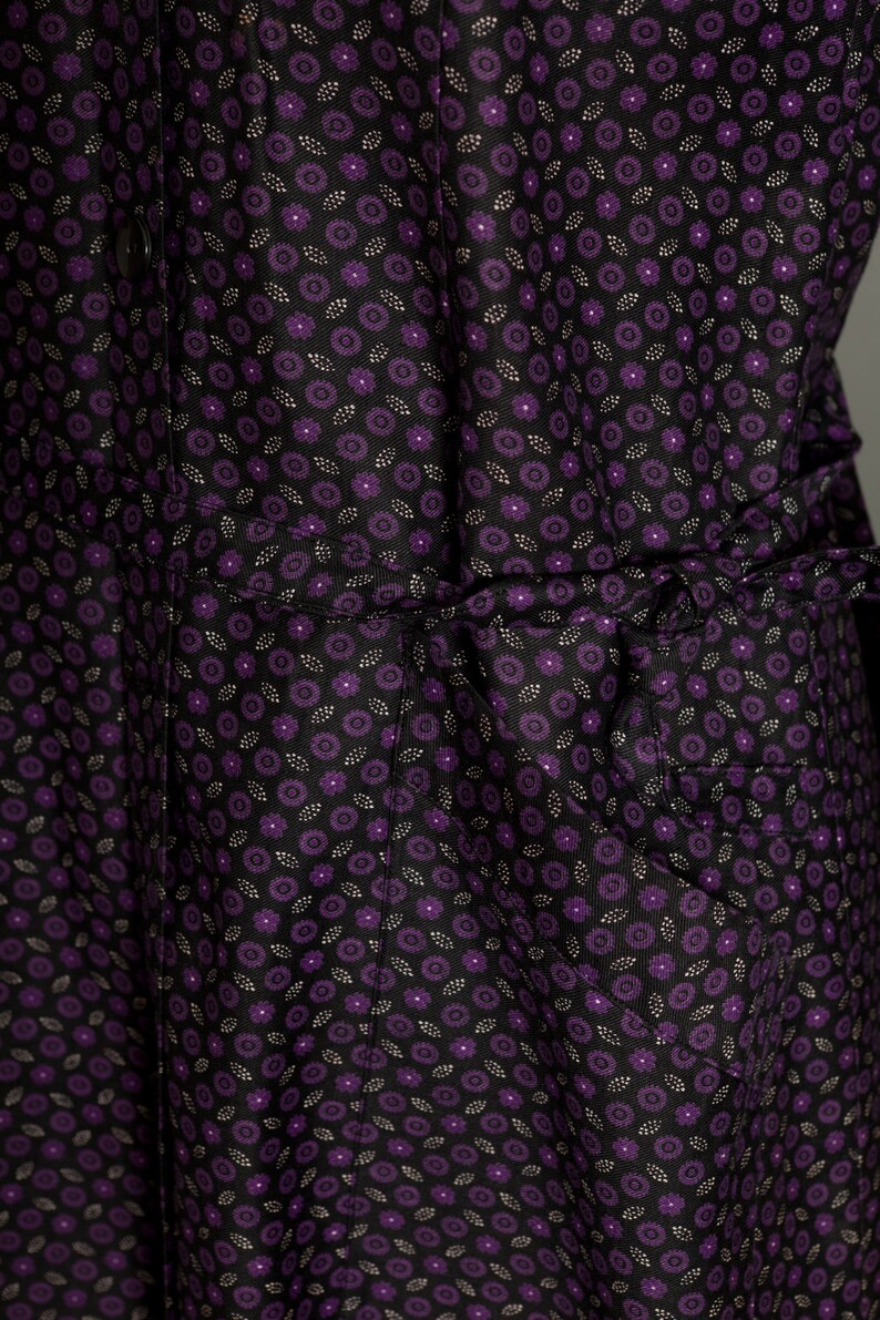 May include: A black dress with a purple floral pattern. The dress has a gathered waist and a ruffled hem.
