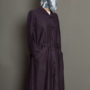 May include: A long-sleeved purple and black patterned shirt dress with a button-up front and a denim patchwork hat.