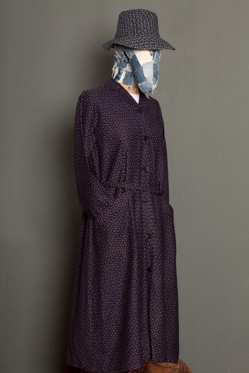 May include: A long-sleeved purple and black patterned shirt dress with a button-up front and a denim patchwork hat.