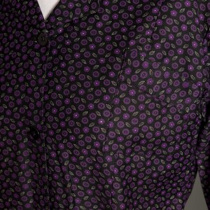 May include: A black button-up shirt with a purple floral pattern. The shirt has a collar and a pocket on the left side.