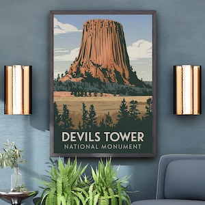 May include: A framed print of Devils Tower National Monument hangs on a teal wall. The print features a brown rock formation, green trees, and the text "Devils Tower National Monument." A blue chair and ottoman with gold trim are in front of the wall.