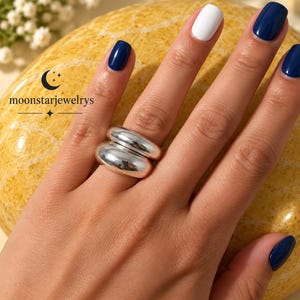 May include: A set of two stacked silver-toned rings with a smooth, rounded, and polished surface. The rings feature a thick, domed band design. The text moonstarjewelrys is visible on the left side of the image along with a crescent moon icon.