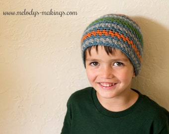 Può includere: Un giovane che indossa un cappello all'uncinetto a strisce blu, verde e arancio. Il cappello ha un'ampia tesa ed è tirato giù sulla fronte della persona. La persona sorride e guarda la telecamera.