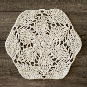 May include: A white crocheted doily with a hexagonal shape and a delicate floral pattern.
