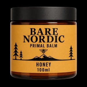Könnte beinhalten: Ein braunes Glasgefäß mit schwarzem Deckel und einem gelben Etikett mit der Aufschrift BARE NORDIC PRIMAL BALM HONEY 100ml. Das Etikett zeigt schwarze grafische Illustrationen von zwei Tannen, einem Gebirge und einer Biene über den Bergen.