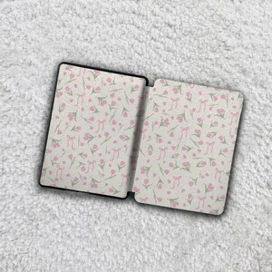 May include: A rectangular e-reader case featuring an all-over pattern of small pink tulips and light pink ribbons on a white background. The case is shown in an open position, displaying the interior panels with the same floral and ribbon design.