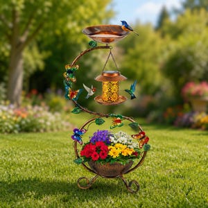 May include: A decorative, bronze-colored bird feeder and flower planter. The feeder has a bowl for water, a solar-powered lantern, and a bird perched on top. The planter holds colorful flowers and is surrounded by butterfly and leaf accents.