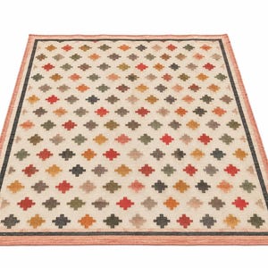 May include: A rectangular area rug featuring a cream-coloured background with a repeating pattern of small, multi-coloured cross shapes in shades of red, orange, green, and dark grey, framed by a dark grey border and a light orange outer edge.