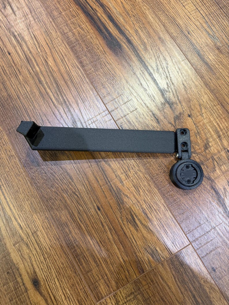 Puede incluir: Un soporte negro para ordenador de bicicleta. Tiene un brazo rectangular con un soporte y un accesorio circular. Dise&ntilde;ado para sujetar un ordenador de ciclismo, est&aacute; hecho de material negro mate. Mide unos 15 cm de largo.