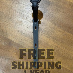 Puede incluir: Soporte negro para ordenador de bicicleta. El soporte está hecho de un material duradero y presenta una parte superior circular para el ordenador y un vástago largo y rectangular con orificios de montaje. El texto "FREE SHIPPING 1 YEAR WARRANTY" es visible.