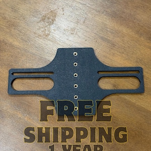 Op de afbeelding: Een zwarte metalen beugel met een reeks kleine gaten en twee langwerpige openingen. De beugel heeft de tekst "FREE SHIPPING 1 YEAR WARRANTY" in goud.