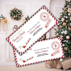 Op de afbeelding: Twee witte enveloppen met rood-wit gestreepte randen. De enveloppen bevatten de tekst "From the Desk of Santa Claus" en "Special Delivery For Olivia Wilson". Er is ook een rendier- en slee-afbeelding aanwezig.