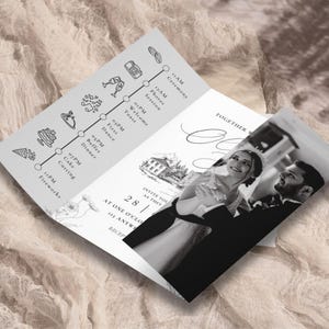 May include: A folded wedding invitation with a timeline of events and a black and white photo of a couple. The invitation includes the text "INVITE YOU AS THEY" and the date "28 / AT ONE O'CLOCK". The background is a neutral color.