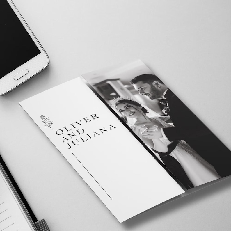 May include: A black and white wedding invitation featuring a photograph of a couple dancing. The invitation has the names "Oliver and Juliana" printed in black, along with a decorative floral element and a vertical line.