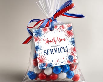 May include: A transparent bag filled with red, white, and blue sweets, tied with a red, white, and blue ribbon. The tag reads "Thank You for Your Service!" in red and blue, with a firework design.