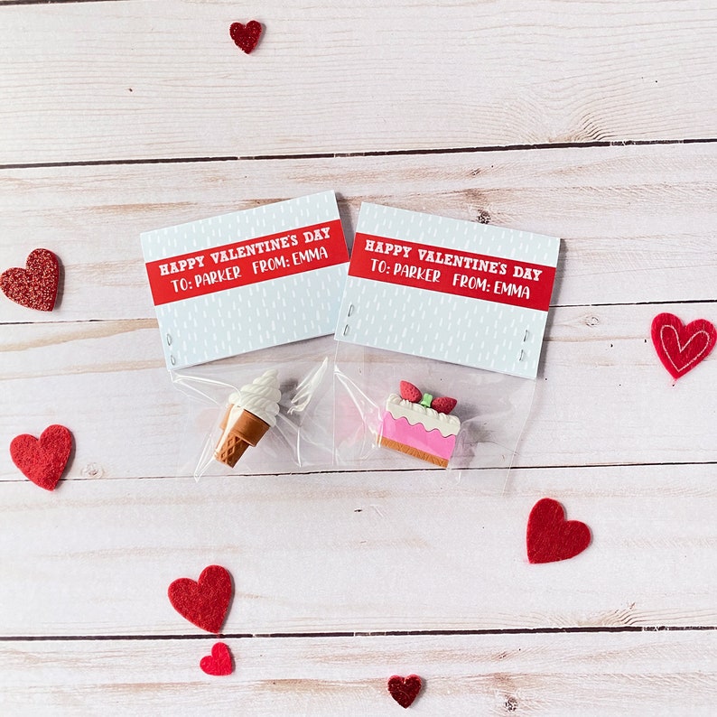 May include: Two small Valentine's Day gift bags with a red and white card that says "Happy Valentine's Day to: Parker From: Emma". One bag contains a small ice cream cone eraser and the other contains a small pink cake eraser.