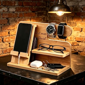 May include: A bamboo docking station featuring a smartphone stand with a charging cable, a shelf for eyeglasses, a horizontal bar for a wristwatch and a smartwatch, and a base tray holding a white earbud case and a set of keys with the text best man David.