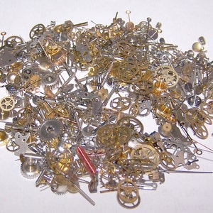 May include: A large collection of assorted watch parts, including gears, springs, and other small metal pieces. The parts are scattered on a white surface.