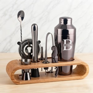 May include: A complete bar tool set in a wooden holder. The set includes a cocktail shaker with the word "Brooklyn" and the letter "D" engraved, a jigger, a strainer, a muddler, a bar spoon, a bottle opener, and other tools.
