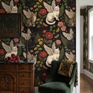Op de afbeelding: Donker behang met een patroon van gevleugelde katten, bloemen en bladeren. De katten zijn wit, zwart en tabby, met gedetailleerde gevederde vleugels. Rode en roze bloemen en vlinders op een zwarte achtergrond.