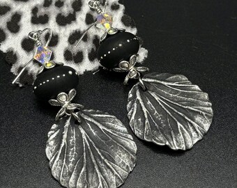 May include: Black and silver earrings with a textured leaf design and a black bead with white dots.