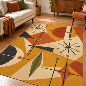May include: A rectangular area rug featuring a geometric pattern with a mustard yellow background, cream-colored sections, and abstract shapes in burnt orange, dark charcoal, and olive green, including starburst motifs and angular lines.