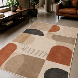 Op de afbeelding: Een rechthoekig vloerkleed met een crèmekleurige basis en een geometrisch patroon van terracotta oranje, antracietgrijze en beige vormen. Het ontwerp bevat gevulde halve cirkels, afgeronde rechthoeken en dunne zwarte lijnboogjes.