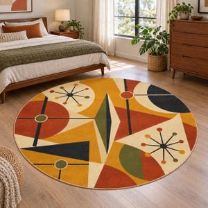 May include: A round area rug featuring a geometric pattern with circles, triangles, and starburst shapes in shades of mustard yellow, burnt orange, dark navy blue, and olive green on a cream background, creating a bold, multi-colored design.