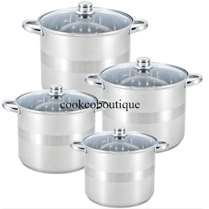 Puede incluir: Un juego de cuatro ollas de acero inoxidable con tapas de cristal. Cada olla tiene una banda plateada en el centro y asas laterales. El texto "cookcoboutique" está impreso en el lateral.