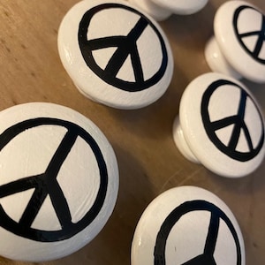 Puede incluir: Seis pomos redondos blancos para armarios con símbolos de paz negros pintados.