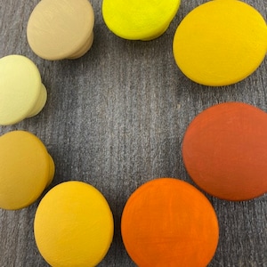 May include: Set of ten round wooden knobs in various shades of yellow and orange. The knobs are painted in a smooth, solid colour.