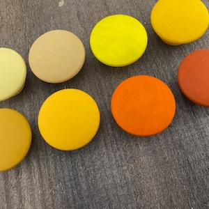 May include: Assortment of 10 round wooden knobs in various shades of yellow and orange. The knobs are smooth and have a matte finish.