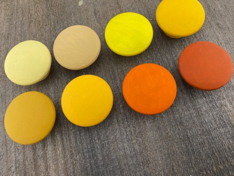 May include: Assortment of 10 round wooden knobs in various shades of yellow and orange. The knobs are smooth and have a matte finish.