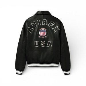 May include: Black leather jacket with white trim on the cuffs and hem. The back displays the word "AVIREX" above a circular emblem with "ALL AMERICANS" and "1975" and the word "USA" below.