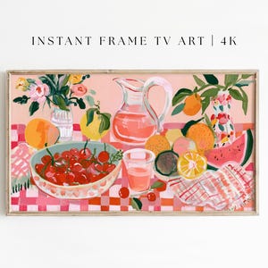 May include: A framed digital art print featuring a still life of fruit and flowers. The artwork includes a bowl of cherries, a pitcher of pink liquid, oranges, lemons, and watermelon on a pink checkered tablecloth. The text "INSTANT FRAME TV ART | 4K" is at the top.