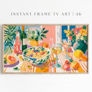 以下が含まれることがあります： 額縁に入ったデジタルアートプリント。鮮やかな静物画が描かれています。パスタ、果物、ワイングラス、ボトルが置かれたテーブルが描かれています。色使いはピンク、オレンジ、緑、青など。上部には「INSTANT FRAME TV ART | 4K」と書かれています。