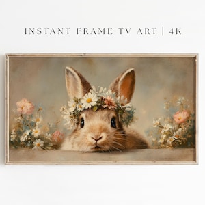 以下が含まれることがあります： デイジーの花冠をつけた茶色のウサギが描かれた、額入りのデジタルアートプリント。ウサギは、柔らかいピンクと白の花に囲まれています。「INSTANT FRAME TV ART | 4K」の文字が上部にあります。