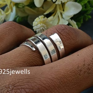 May include: A silver ring with a wrap-around design, featuring three flat bands and a spiral detail. The ring is shown on a finger, with the text "925jewells" visible in the image.