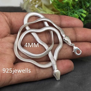 May include: A silver-colored snake chain necklace featuring a 4MM width and a lobster claw clasp. The metal chain has a smooth, flexible, and segmented design. The text 4MM and 925jewells is printed on the image in white lettering.