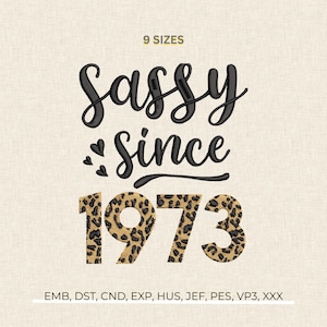 Peut inclure: Un motif de broderie avec le texte "Sassy Since 1973". Le mot "Sassy" est écrit en noir dans une police script, et "Since" dans une police similaire. Les chiffres "1973" ont un motif léopard. Les mots "9 SIZES" sont en haut.