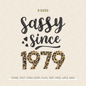 May include: An embroidered design with the words "Sassy Since 1979". The word "Sassy" is in a black script font, and "Since" is in a smaller black script font. The numbers "1979" are in a leopard print pattern.