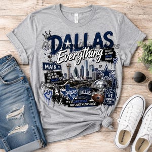 Puede incluir: Una camiseta gris jaspeado con un estampado gráfico del horizonte de Dallas, un longhorn, un casco de fútbol americano y un dedo de espuma. El texto dice DALLAS, Everything, MAIN ST, DEEP IN THE HEART OF DALLAS, BIG CITY BIG HEART DALLAS FOREVER e IT'S A LIFESTYLE, NOT JUST A ZIP CODE.
