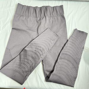 May include: Grey seamless leggings with a high waistband. The leggings have textured patterns on the lower legs. The fabric appears to be a soft, stretchy material, suitable for athletic activities or casual wear.