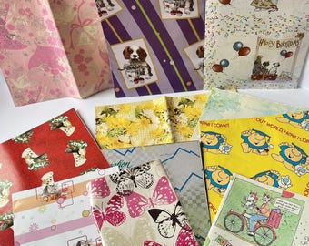 Puede incluir: Una colección de hojas de papel de regalo coloridas con varios diseños. Los diseños incluyen cachorros, mariposas, flores y temas de cumpleaños. Algunas hojas presentan texto como "Happy Birthday" y "Here I come!"