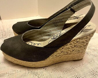 May include: Black peep-toe wedge sandals with a woven jute sole. The sandals have a slingback strap and a fabric upper. The brand name "kenz" is visible on the insole. The wedge heel is approximately 3 inches high.