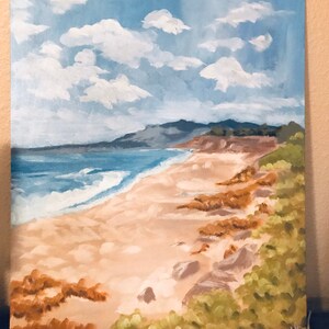 May include: A painting of a beach scene with a blue ocean, white waves, and a sandy shore. The beach is lined with green bushes and brown rocks. The sky is blue with white clouds.
